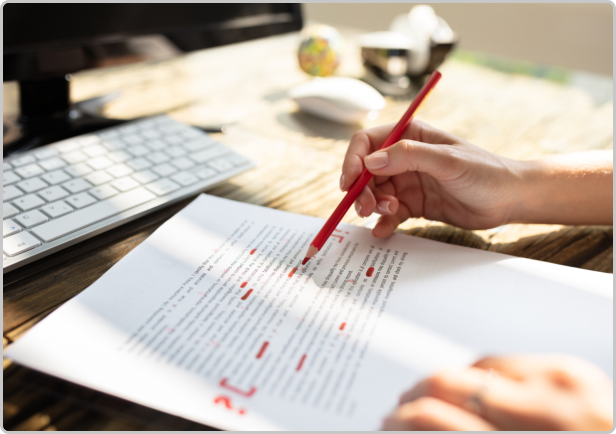 hand holding a red correction pencil editing a document